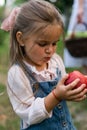 ÃÂ¡ute little girl is holding a red apple in the garden